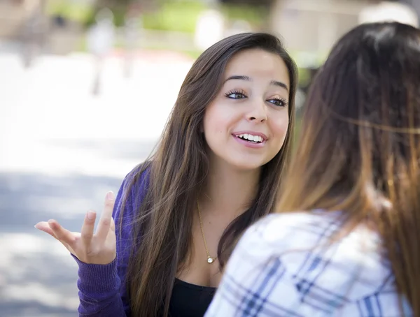 Expresivo joven mixta raza hembra sentado y hablando con chica — Foto de Stock