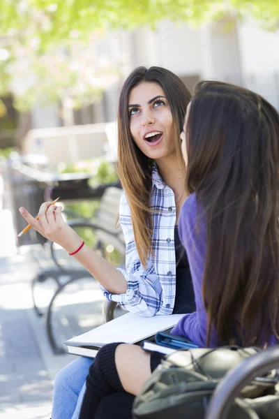 Expresivo joven mixta raza hembra sentado y hablando con chica — Foto de Stock