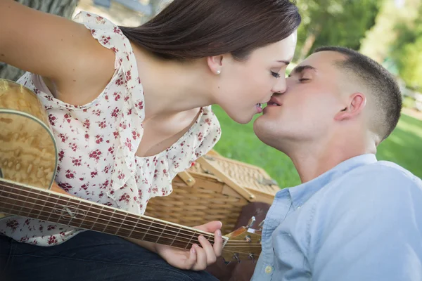 Blandras par med gitarr kyssar i parken — Stockfoto
