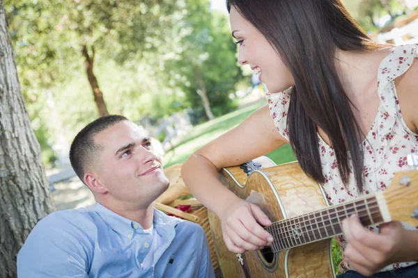 Casal de corrida mista no parque tocando guitarra e canto — Fotografia de Stock