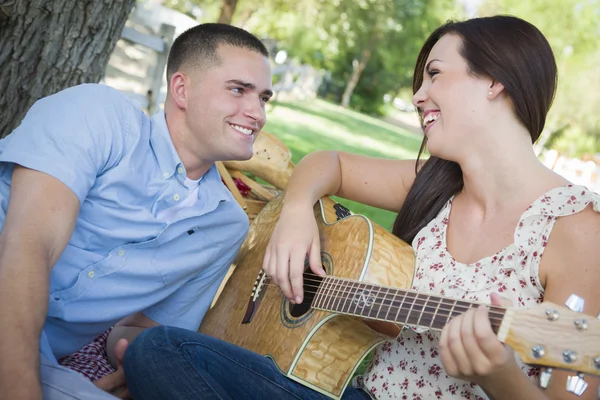 Pareja de carrera mixta en el parque tocando guitarra y cantando — Foto de Stock