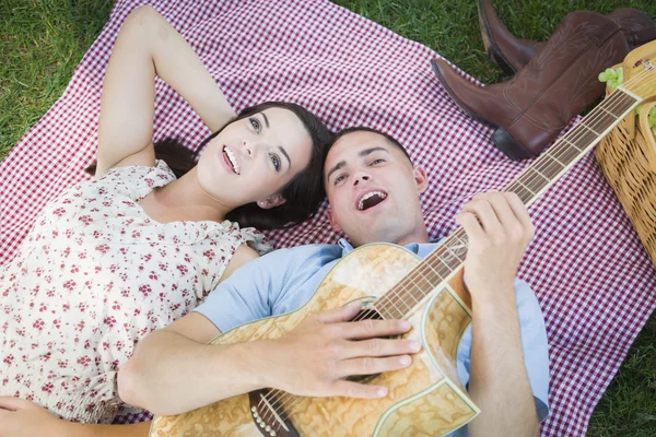 Casal de corrida mista no parque tocando guitarra e canto — Fotografia de Stock