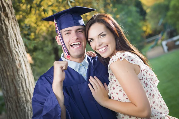 Homme diplômé en casquette et robe et fille célèbrent — Photo
