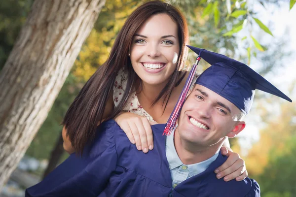 Homme diplômé en casquette et robe et fille célèbrent — Photo