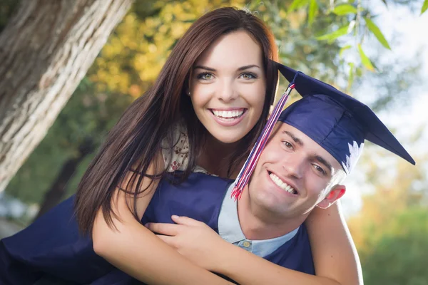 Homme diplômé en casquette et robe et fille célèbrent — Photo