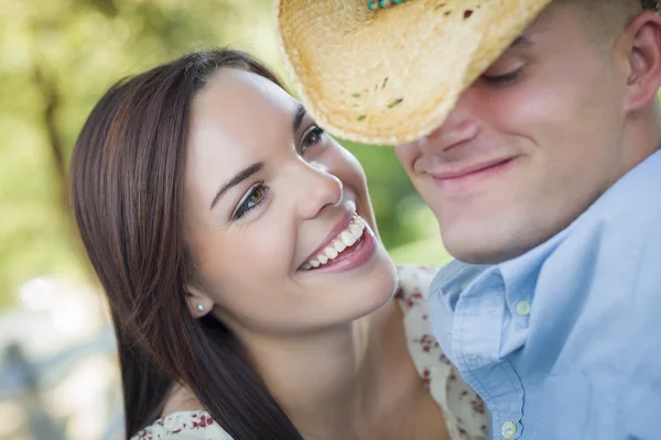 Casal romântico de raça mista com chapéu de cowboy flertando no parque — Fotografia de Stock