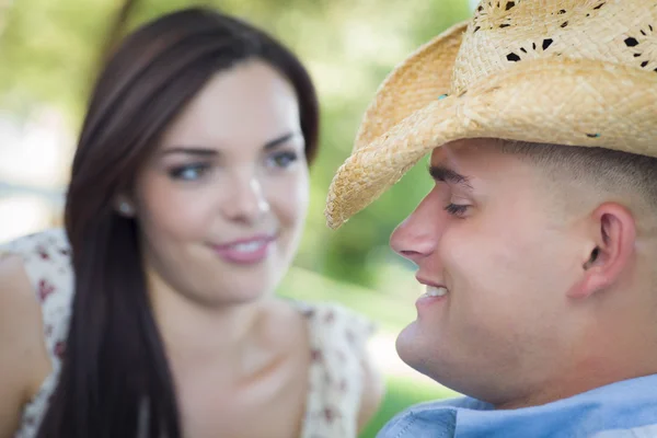Casal romântico de raça mista com chapéu de cowboy flertando no parque — Fotografia de Stock