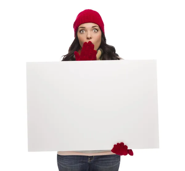 Chica aturdida con sombrero de invierno y guantes sostiene signo en blanco Imagen de archivo