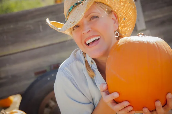 Schöne blonde Rancherin mit Cowboyhut hält einen Kürbis — Stockfoto