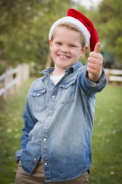 Ung pojke bär semester kläder ger tummen upp utanför — Stockfoto