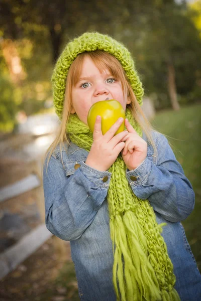 Jong meisje dragen groene sjaal en muts eten apple buiten — Stockfoto