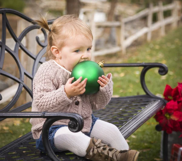 Kleinkind sitzt draußen auf Bank mit Weihnachtsschmuck — Stockfoto