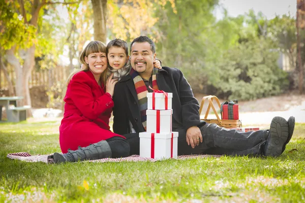 Família de raça mista desfrutando de presentes de Natal no parque juntos — Fotografia de Stock