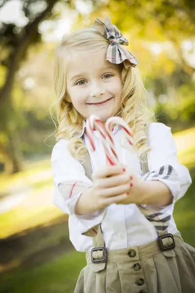 Cute dziewczynka trzymając Boże Narodzenie słodycze laski na zewnątrz — Zdjęcie stockowe