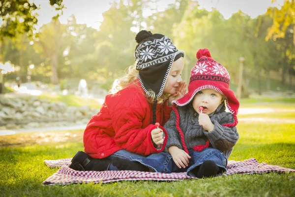 Klein meisje fluistert een geheim aan baby broer buitenshuis — Stockfoto