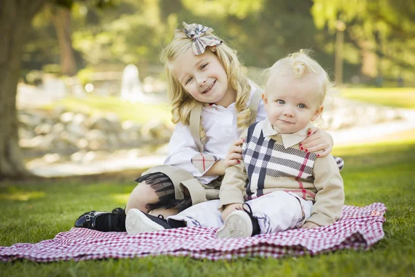 Милая маленькая девочка обнимает своего младшего брата в парке — стоковое фото