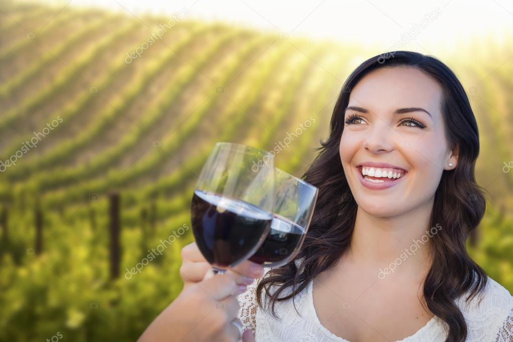 Young Woman Enjoying Glass of Wine in Vineyard With Friends