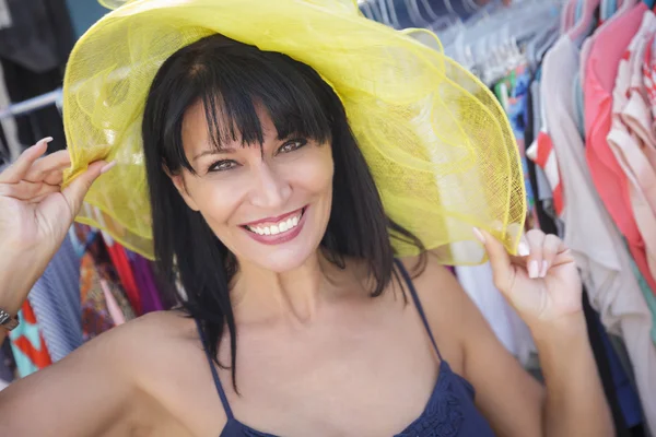 Bella donna italiana che prova il cappello giallo al mercato — Foto Stock