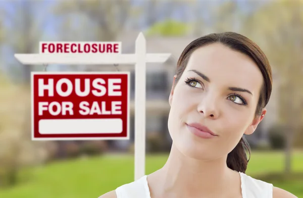 Mujer de raza mixta en frente de la casa y el signo de ejecución hipotecaria —  Fotos de Stock