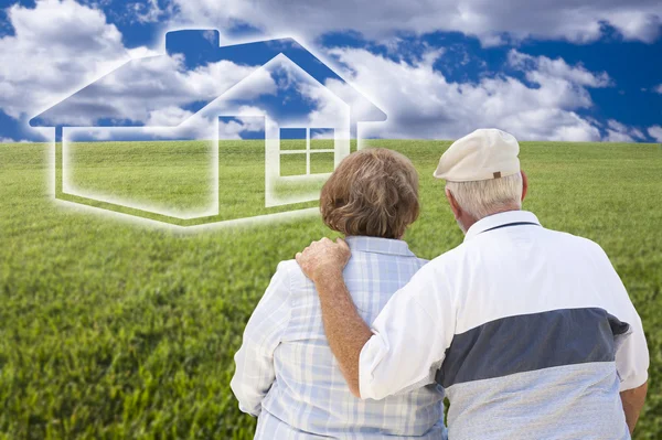 Senior koppel staande in grasveld kijken naar gedimde huis — Stockfoto