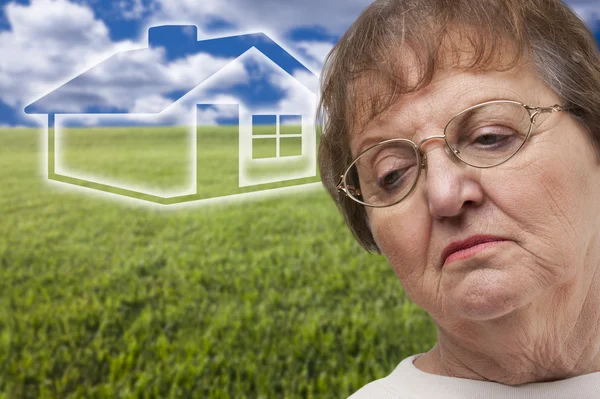 Femme âgée mélancolique avec champ d'herbe et maison fantôme Behin — Photo