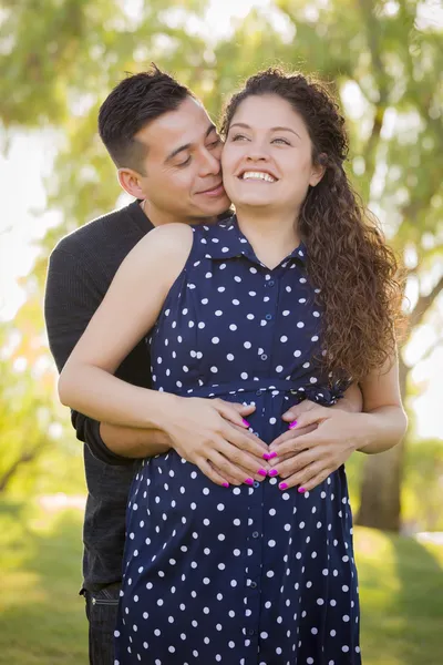 Hombre hispano abraza a su esposa embarazada al aire libre en el parque —  Fotos de Stock