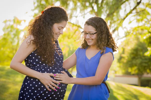 Filha hispânica sente bebê chutar na barriga da mãe grávida — Fotografia de Stock