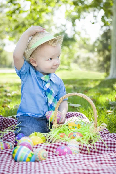 Lindo niñito afuera sosteniendo huevos de Pascua inclina su sombrero —  Fotos de Stock