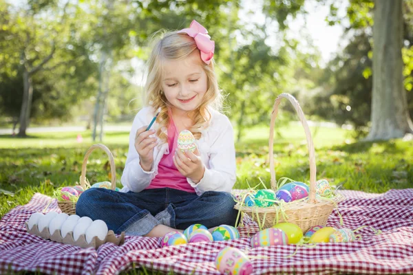 Милая молодая девушка раскрашивает пасхальные яйца кистью — стоковое фото