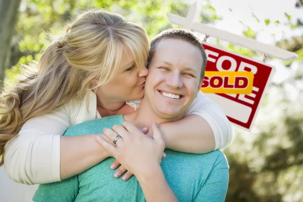 Gelukkige paar vooraan verkocht onroerend goed teken — Stockfoto