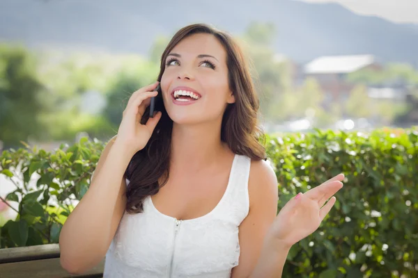 Giovane donna adulta che parla sul telefono cellulare all'aperto sul banco — Foto Stock