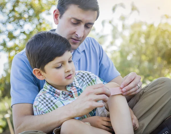 Pai amoroso coloca bandagem no joelho do jovem filho — Fotografia de Stock
