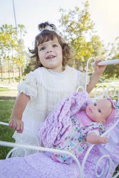Entzückendes junges Mädchen spielt mit Puppe und Kinderwagen — Stockfoto
