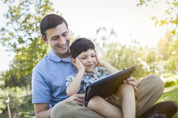 Yakışıklı karışık ırk baba ve oğul bilgisayar tablet üzerinde oynama — Stok fotoğraf