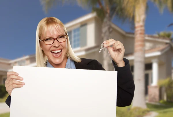 Mujer emocionada sosteniendo las llaves de la casa y el signo de bienes raíces en blanco —  Fotos de Stock