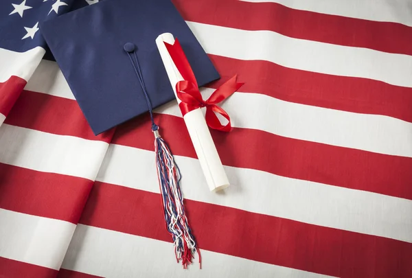 Graduação Cap e Diploma descansando na bandeira americana — Fotografia de Stock