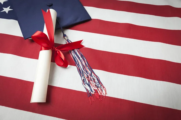 Graduation Cap and Diploma Resting on American Flag — Stock Photo, Image