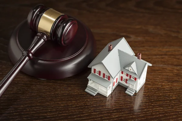 Gavel e pequena casa modelo na mesa — Fotografia de Stock