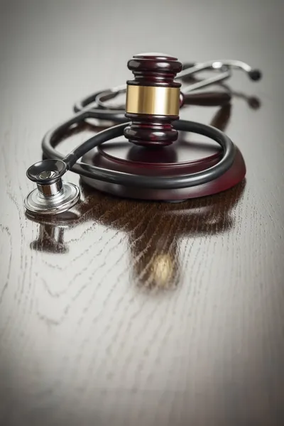 Gavel e estetoscópio na mesa reflexiva — Fotografia de Stock