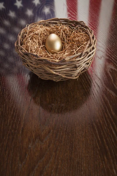 Goldenes Ei im Nest mit Spiegelung der amerikanischen Flagge auf dem Tisch — Stockfoto