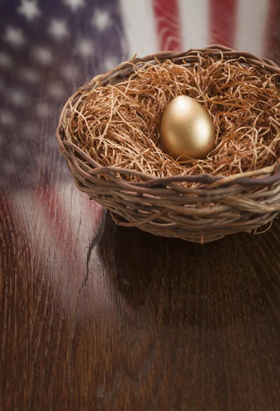 Goldenes Ei im Nest mit Spiegelung der amerikanischen Flagge auf dem Tisch — Stockfoto