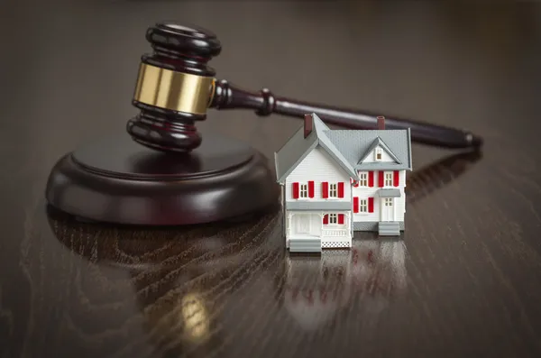 Gavel e pequena casa modelo na mesa — Fotografia de Stock