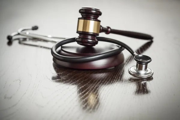 Gavel e estetoscópio na mesa reflexiva — Fotografia de Stock