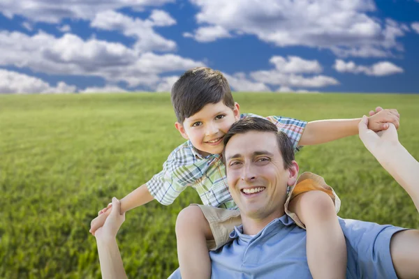 Gemengd ras vader en zoon piggyback spelen op grasveld — Stockfoto