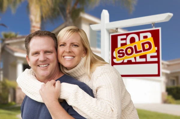 Pareja en frente de Vendido Signo de Bienes Raíces y Casa — Foto de Stock