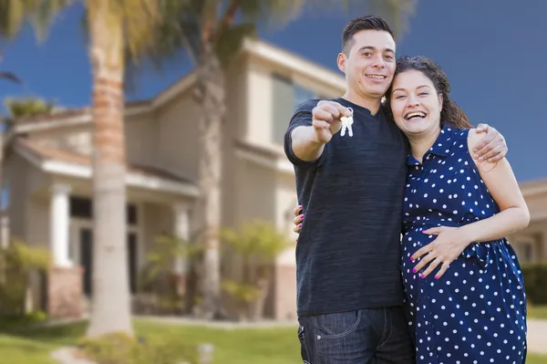 Pareja hispana con llaves de la casa frente a un nuevo hogar — Foto de Stock