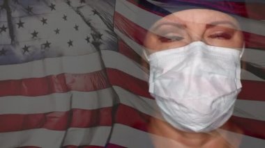 Kadın doktor ya da hemşire cerrahi maske takıyor ve ağır ağır hareket eden ağır çekimde Amerikan bayrağı sallanıyor..