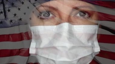 Kadın doktor ya da hemşire tıbbi maske takıyor ve kameraya bakıyor. Amerikan bayrağı sallayan ağır çekimle birleşmiş..