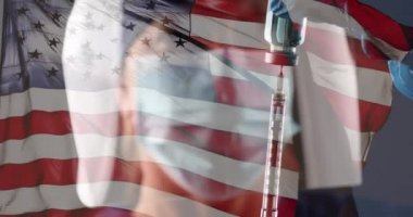 4k Doktor ya da Hemşire PPE ve yüz kalkanı ile aşı şişesi ve şırınga ile birlikte Amerikan Bayrağı Dalgalanan Yavaş Hareketli.