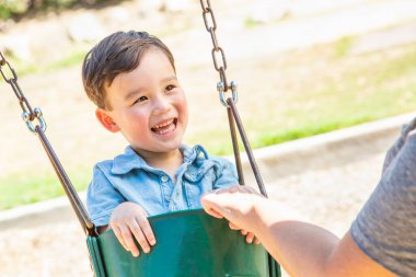 Çinli ve Kafkasyalı çocuk oyun sahasında salıncakta eğleniyor..